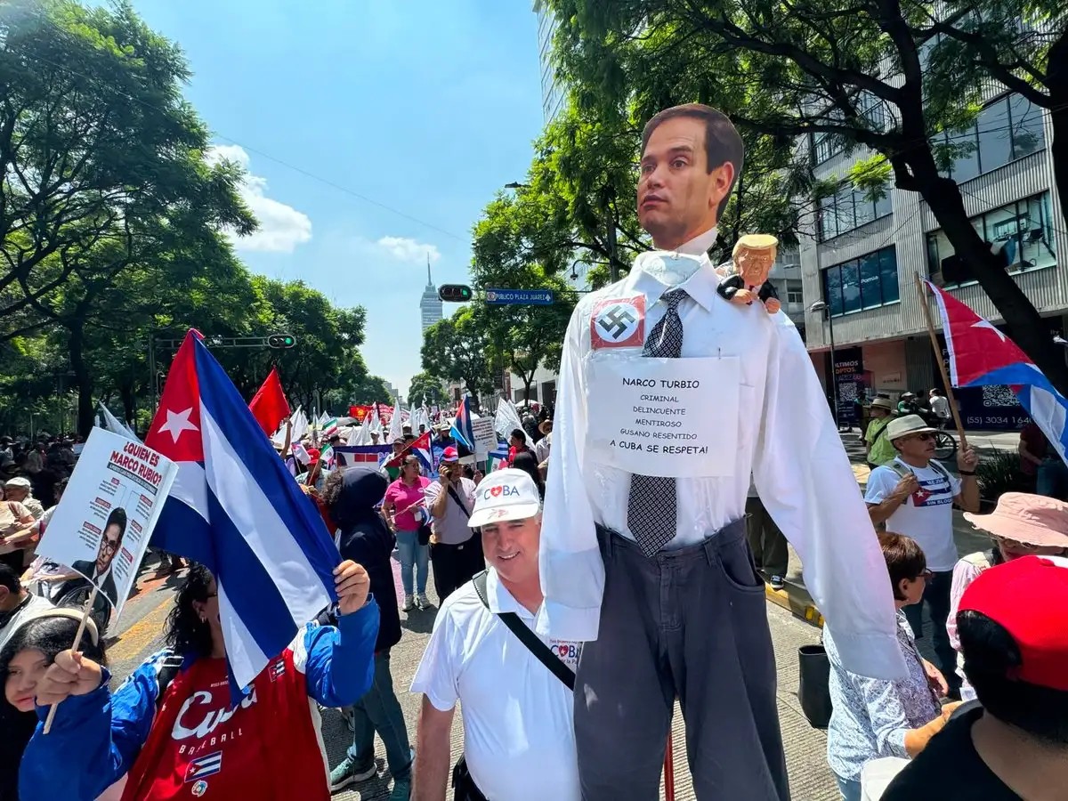 An effigy caricaturing US Secretary of State Marco Rubio holding a Trump puppet is carried through the march