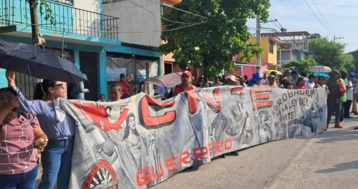 Members of the CETEG teachers' union hold a banner during President Sheinbaum's visit to Acapulco