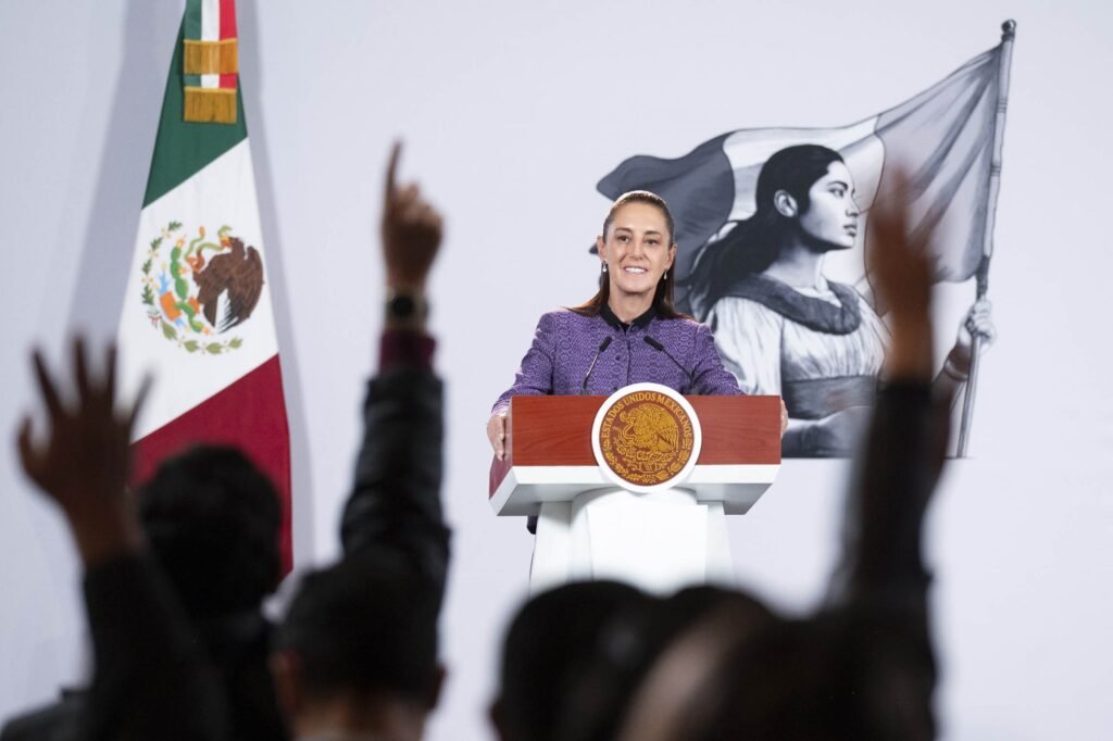 President Claudia Sheinbaum smiles at the podium during her morning press conference at the National Palace as reporters raise their hands, September 30, 2026.