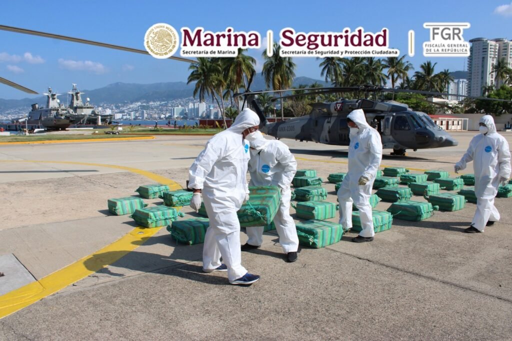Navy personnel in protective suits unload packages of seized cocaine next to a helicopter