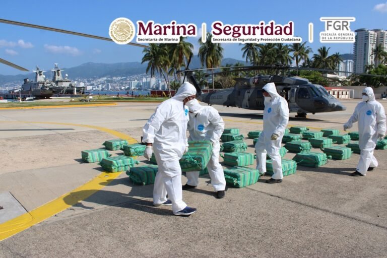 Navy personnel in protective suits unload packages of seized cocaine next to a helicopter