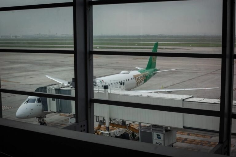 Aircraft at a jet bridge seen through an airport terminal window